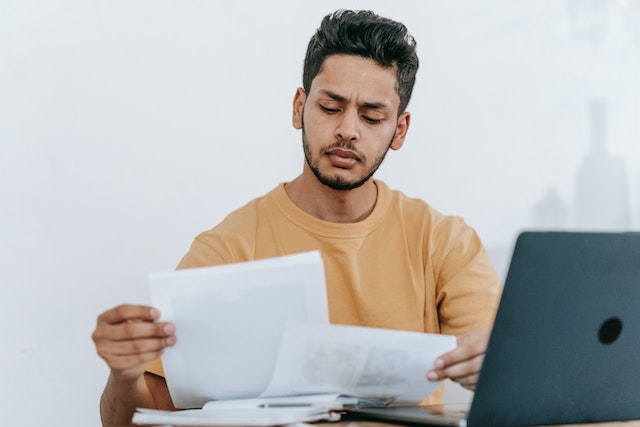 property-manager-wearing-yellow-sweater-reads-tenant-application-at-desk