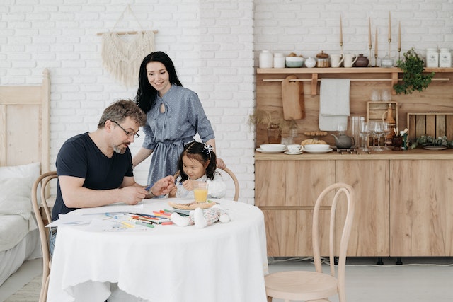 parents-sitting-at-table-with-toddler-reading